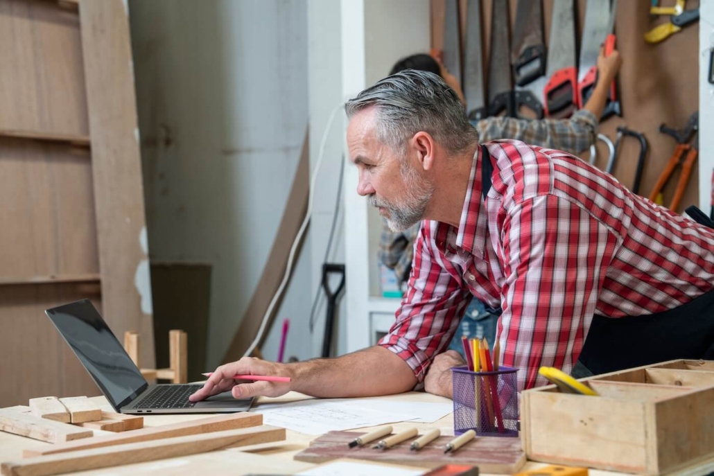 Senior male carpenter looking at laptop image