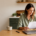 Woman reading a document. Laptop, pen, and mug on her table.